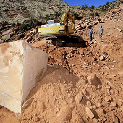 Heavy equipment on the side of a mountain with two workers and big rocks.