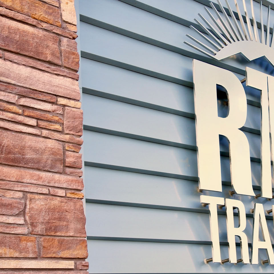 Building exterior with a stone wall on the left and a sign reading "RTC Transit" on the right.