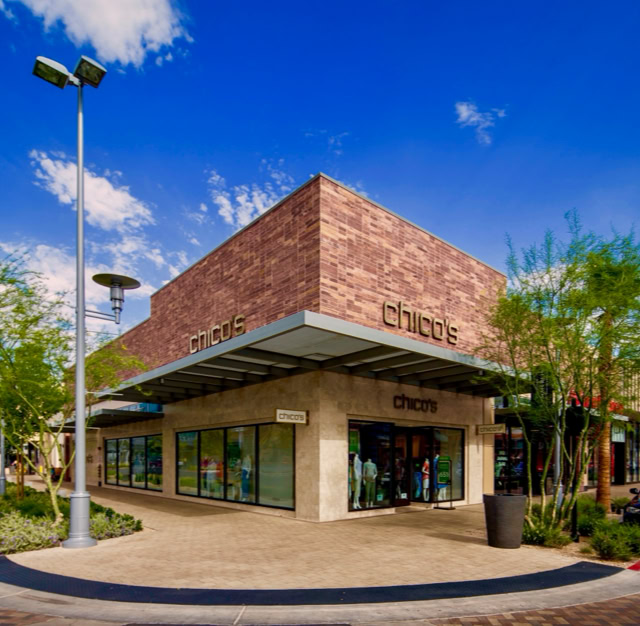 A modern Stone building with large glass windows, surrounded by trees and a streetlamp, under a clear blue sky. At downtown summerlin center in las vegas nv.